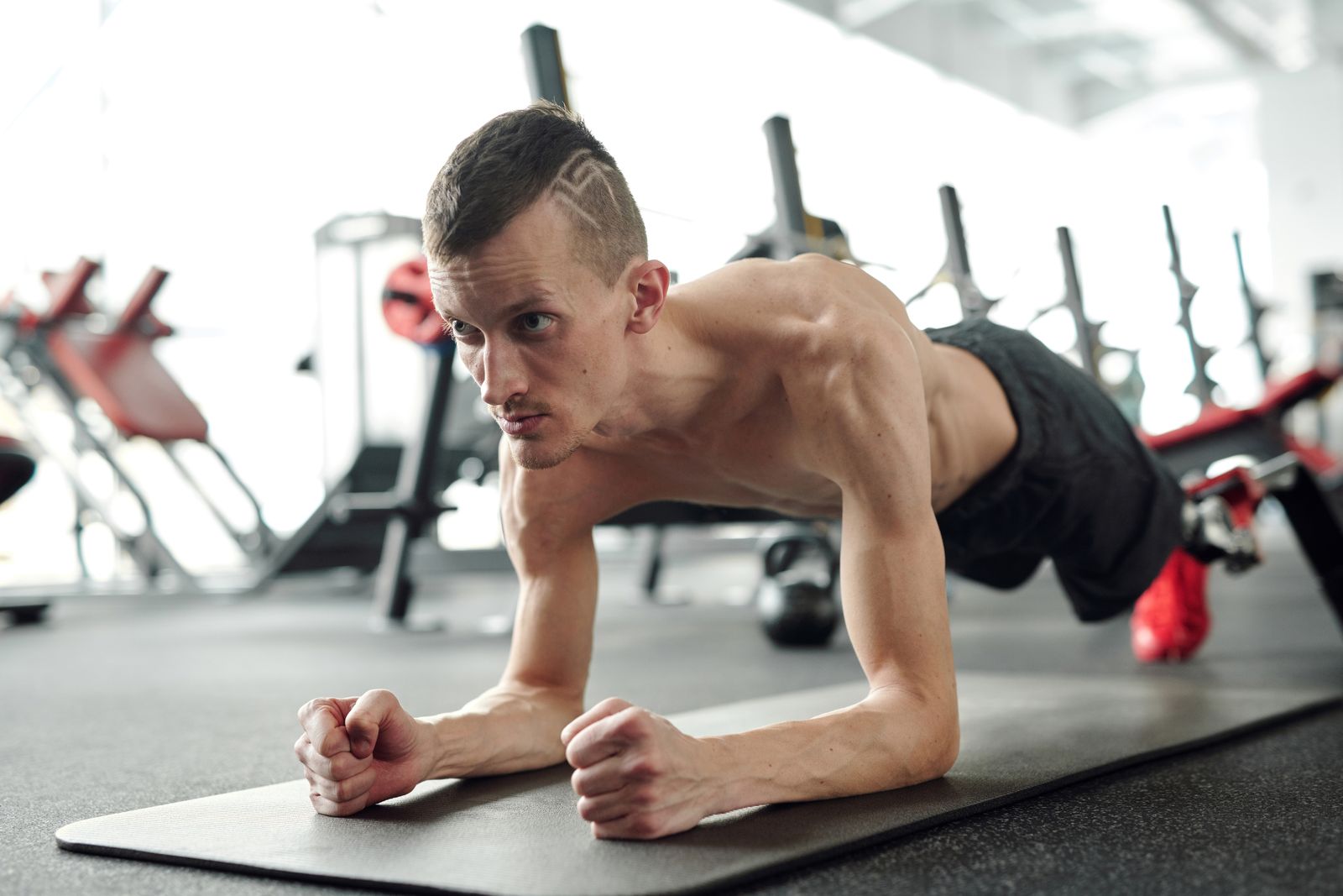 A side-by-side comparison: on the left, a man performing a Pallof press at chest height, resisting the rotational pull of a cable with a braced core and neutral spine; on the right, a man in a loaded farmer's carry position holding heavy dumbbells at his sides, torso upright, walking with engaged core.