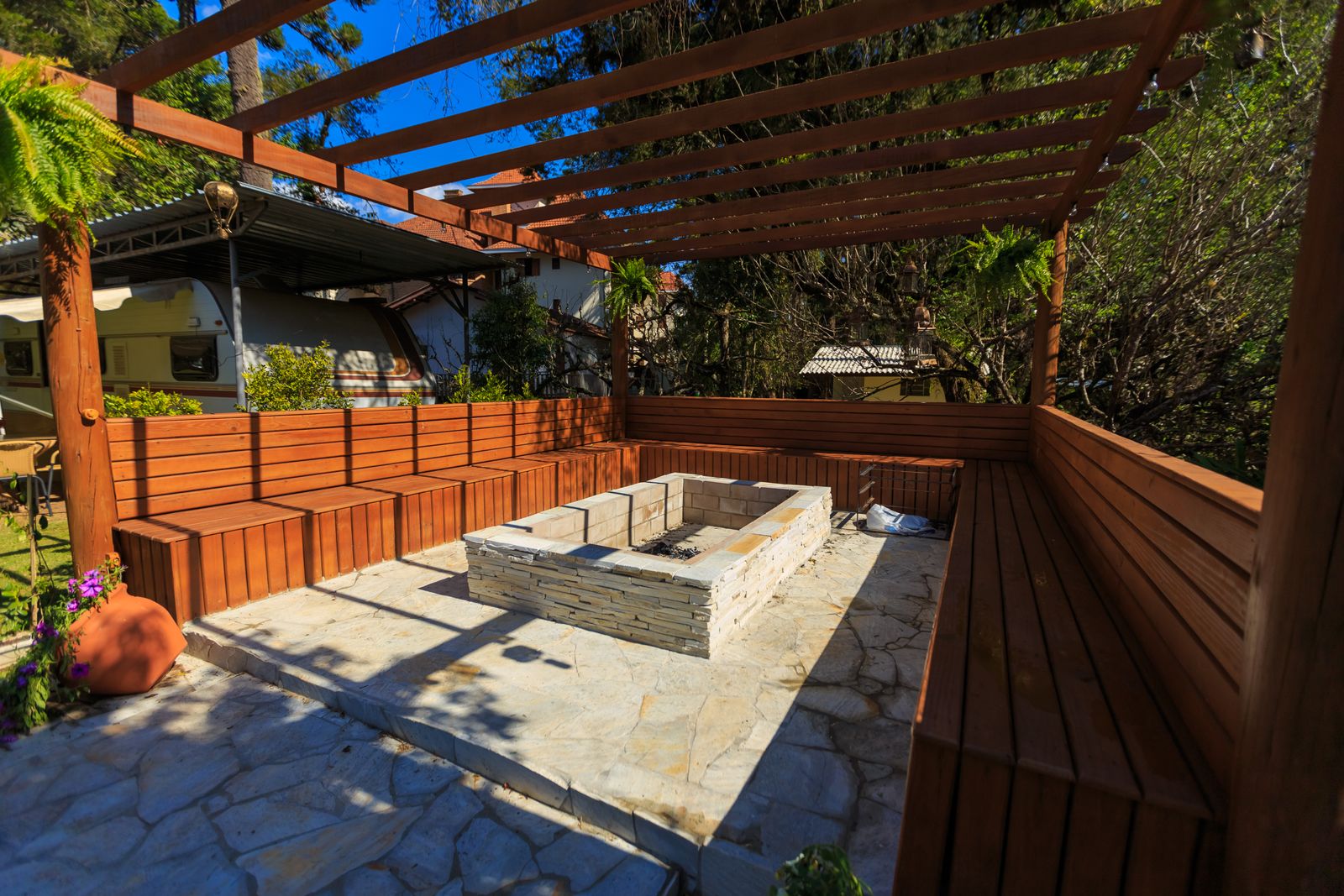 A sectional diagram of a completed backyard fire pit showing the stone and paver foundation, the metal fire ring seated in the top edge, the gravel and stepping-stone floor, and a vertical measurement line marking the 12-14 inch height from ground to ring opening.