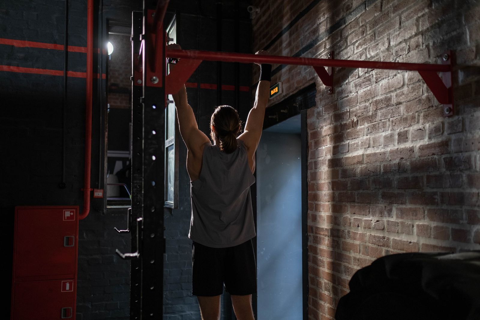 Technical breakdown diagram showing the four-phase progression from dead hang through scapular retraction, band-assisted pull-up with proper grip width and elbow positioning, and strict pull-up form—overhead and side-profile views highlighting scapular positioning, arm angles, and body alignment at each stage, with color-coded muscle activation (lats, back, shoulders) and common form errors in red.