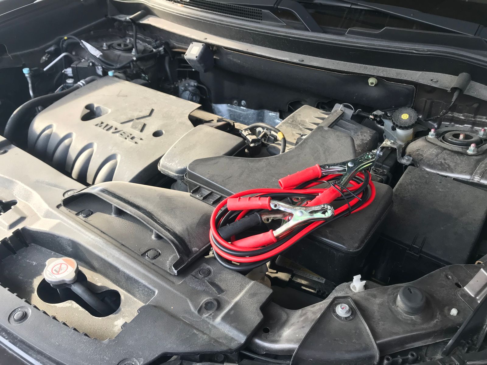 Diagram showing the four-step clamp connection sequence for jump-starting a car: red clamp to dead battery positive terminal, red clamp to donor battery positive terminal, black clamp to donor battery negative terminal, and black clamp to unpainted metal ground on the dead car's engine block. Arrows indicate correct connection order and timing.