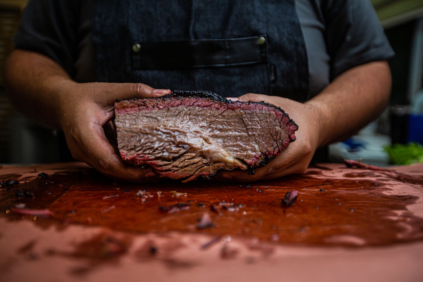 Cross-section diagram of a trimmed packer brisket showing the flat and point, with the ¼-inch fat cap on top and grain direction marked for slicing against the grain.</illustrationAlt>
</invoke>