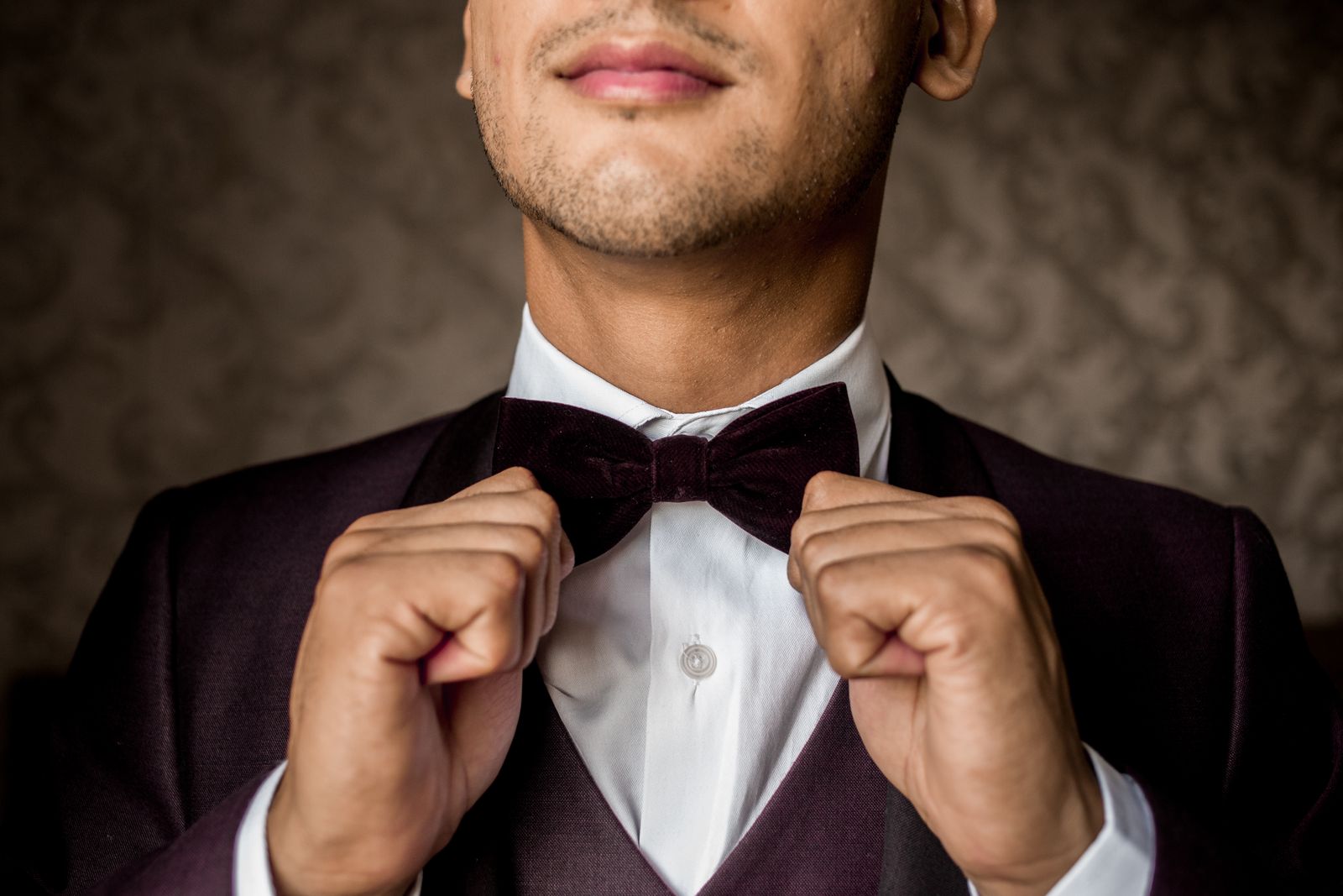 Technical diagram showing the eight-step bow-tie tying sequence in overhead view, with close-up details of hand positioning at the critical threading and loop-forming stages, displayed alongside a side profile showing the finished bow tie positioned on a man's neck with a formal dress shirt and tuxedo jacket, demonstrating proper placement relative to the collar points.