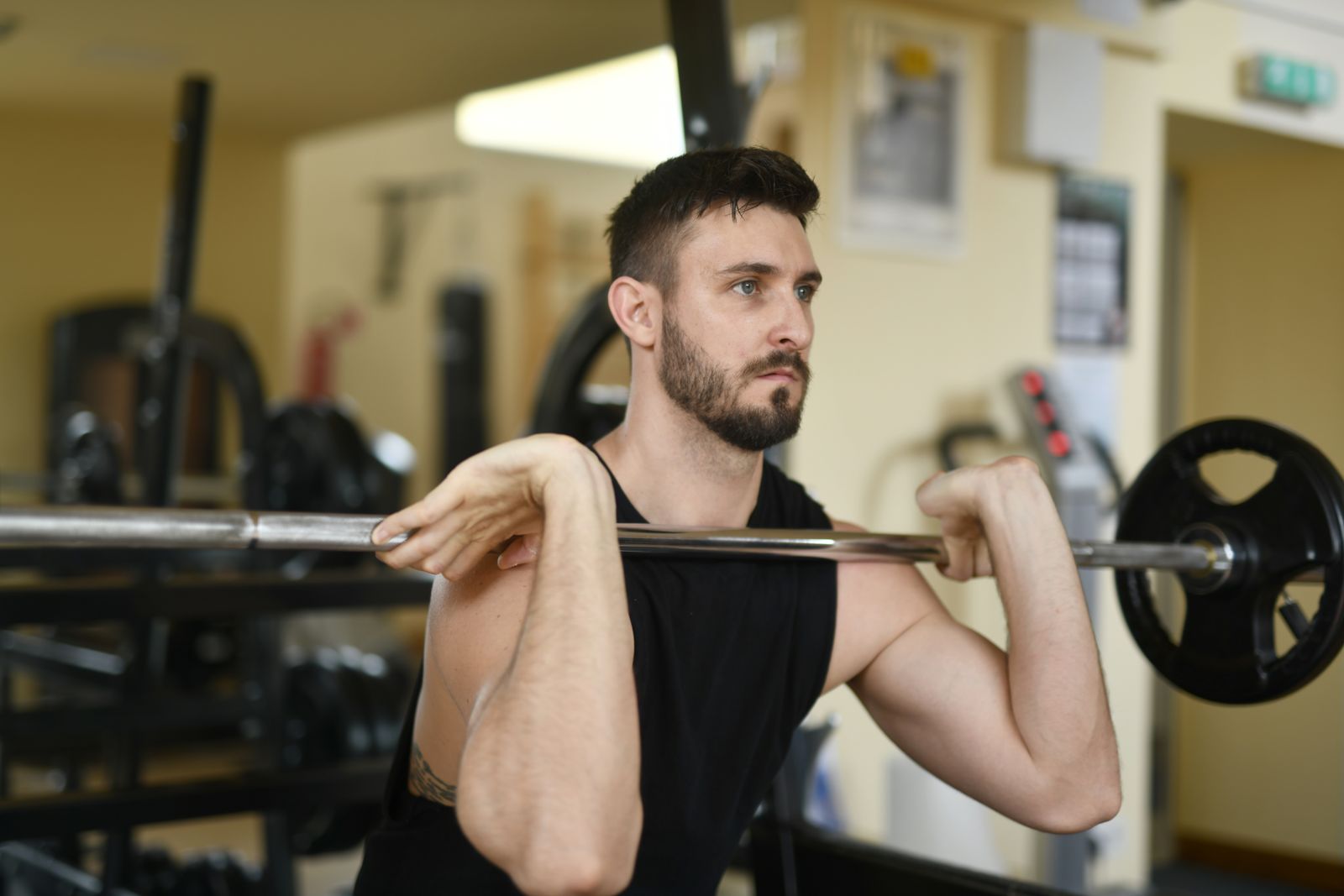 A fitness professional performing a barbell back squat with proper form: feet shoulder-width apart, knees tracking over toes, chest upright, bar positioned across rear deltoids, descending to parallel depth.</illustrationAlt>
</invoke>