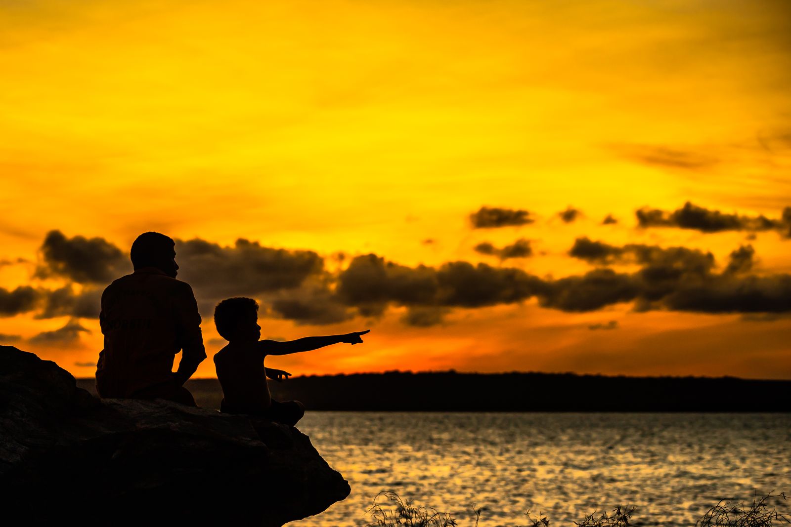 A father resting his hand on his young son's shoulder in a quiet doorway, head bowed in prayer, warm morning light.