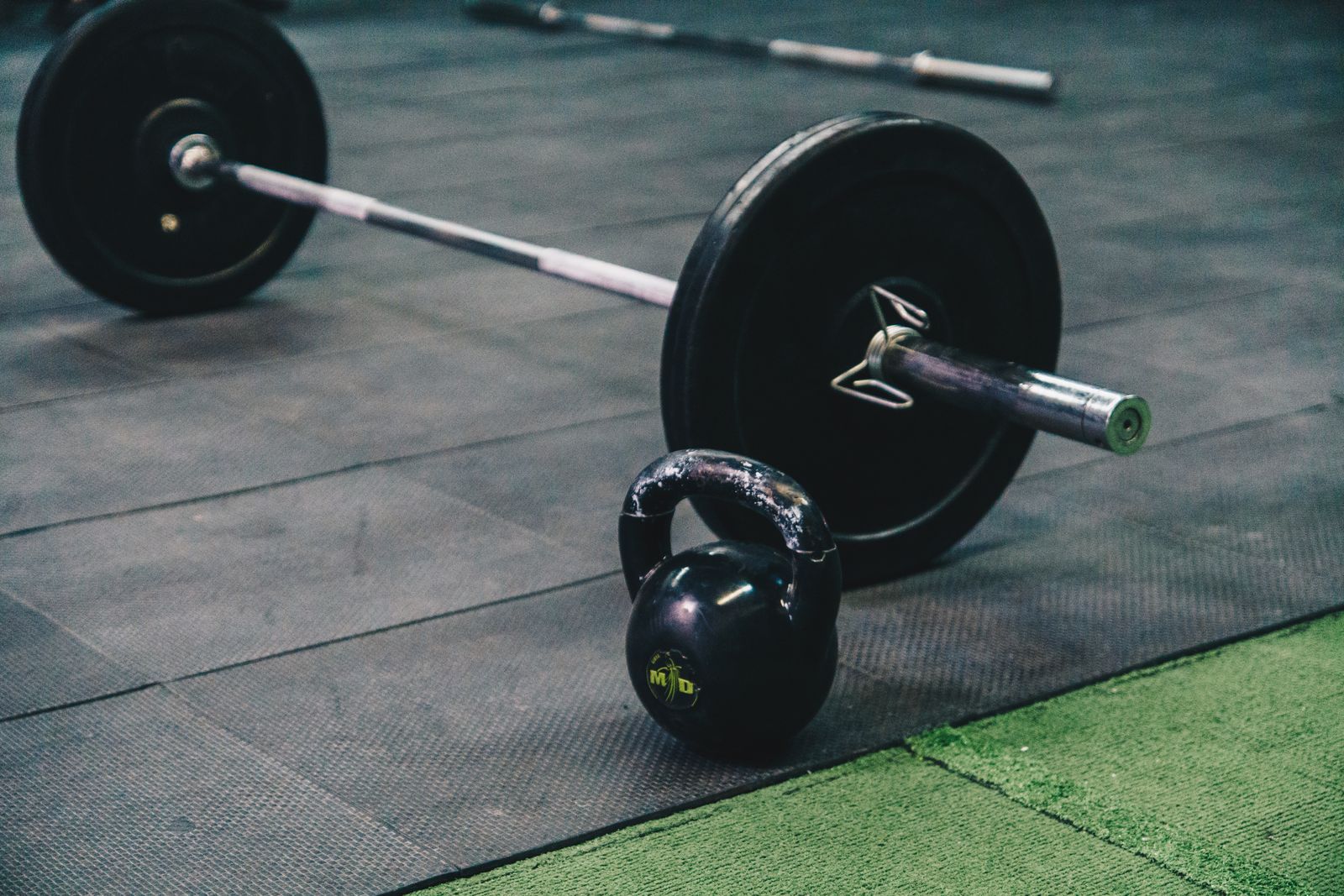A male lifter performing a barbell back squat in a gym setting, demonstrating proper form with chest upright, bar positioned across the upper back, and depth at parallel (thighs level with the floor), with a neutral expression and controlled positioning typical of beginner strength training.